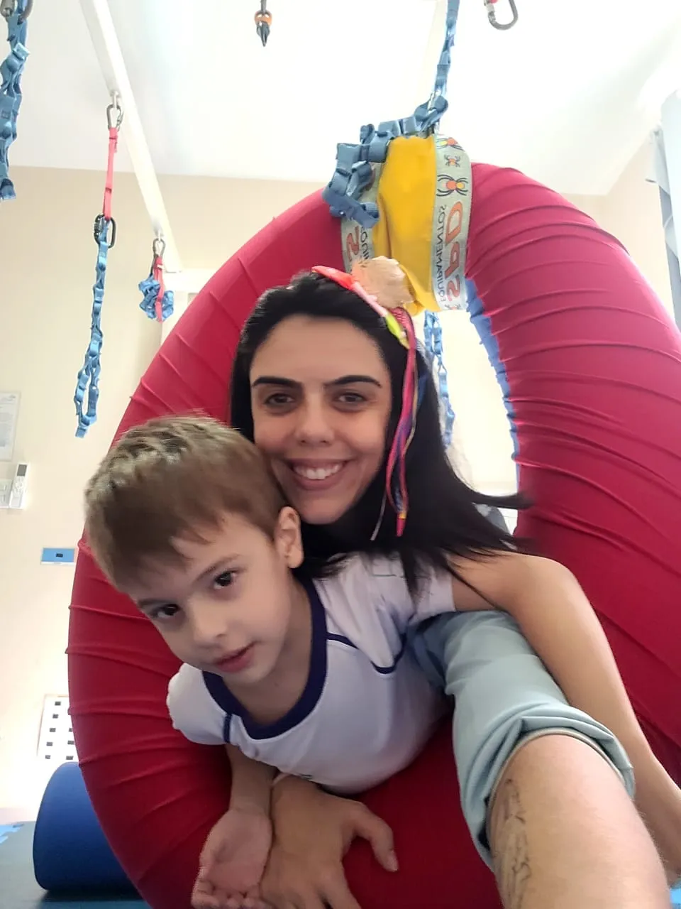 Rebeca e uma criança sorrindo juntas em um balanço