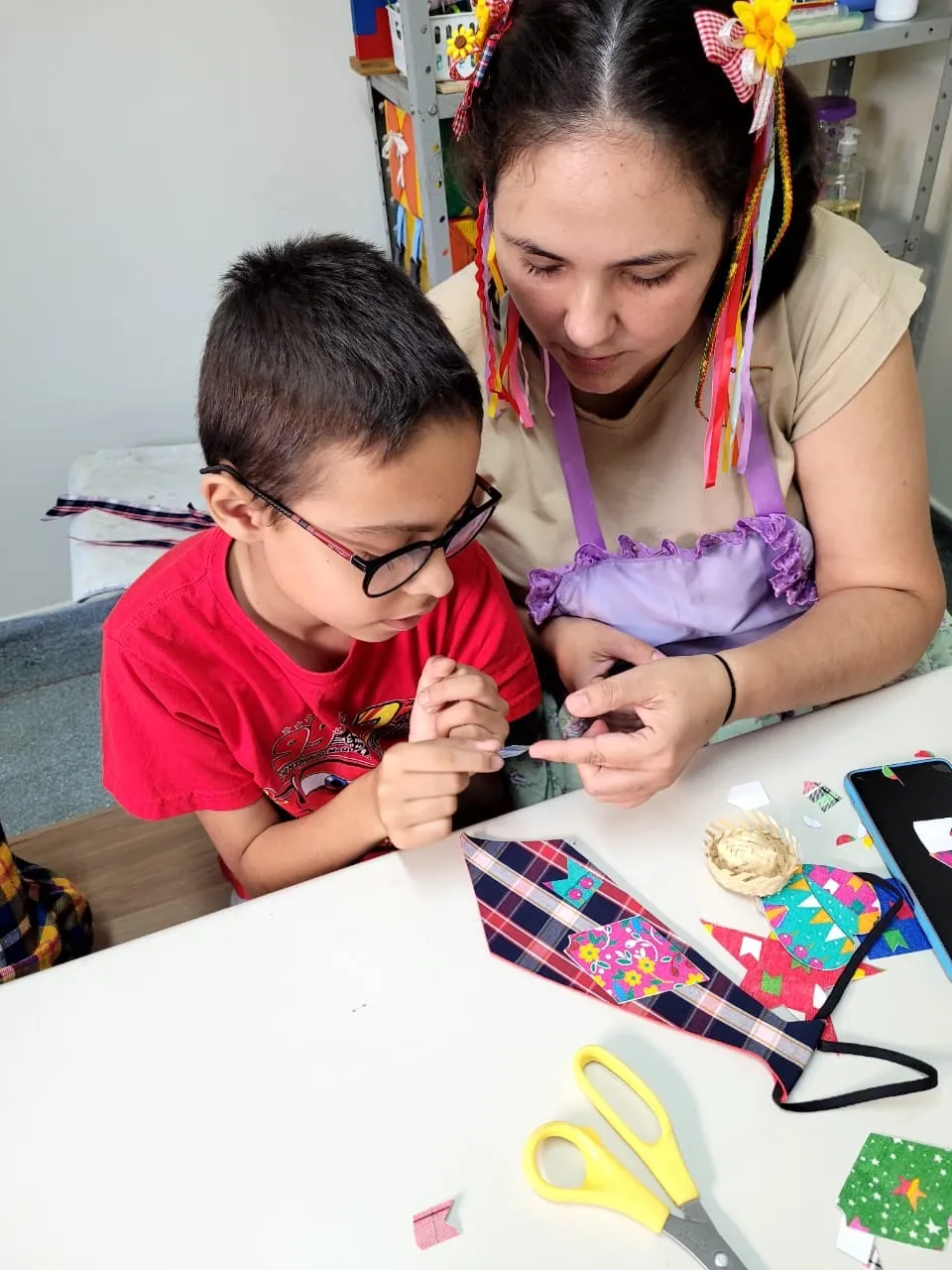 Menino de óculos brincando com jogo de encaixe ao lado da terapeuta