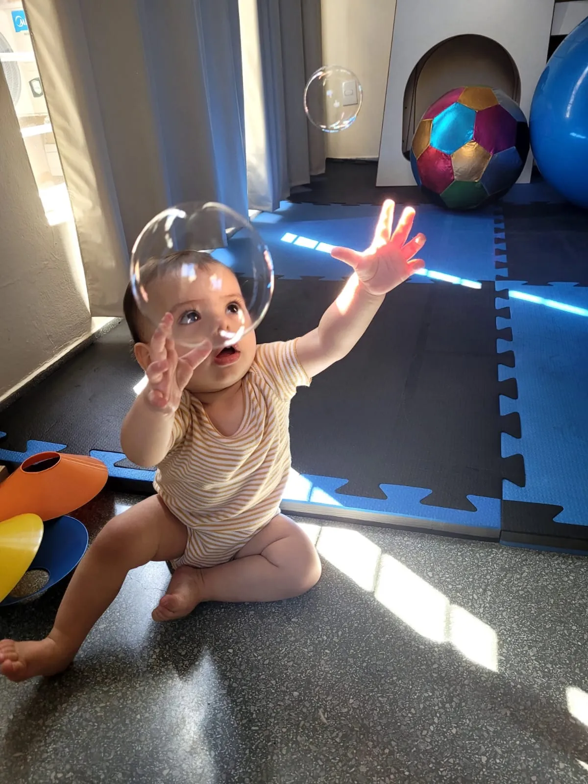 Bebê em pé com apoio, brincando com um brinquedo luminoso