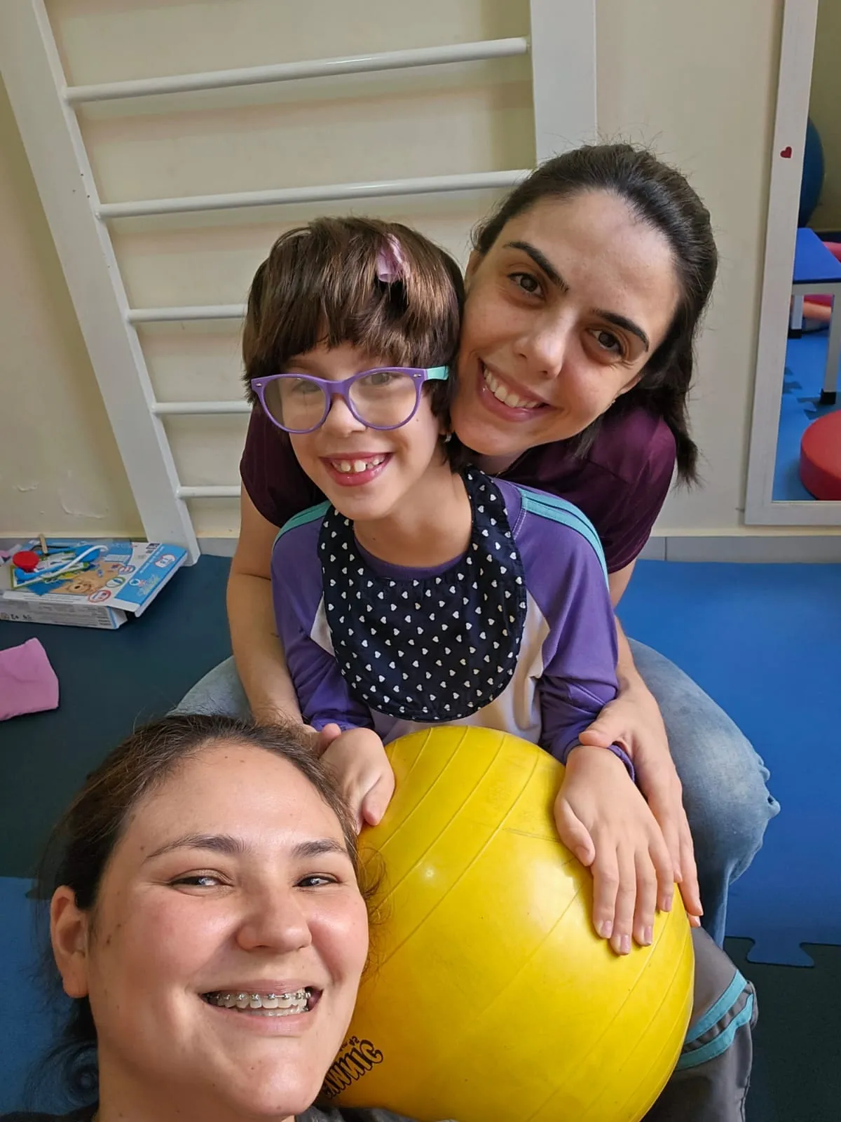 Rebeca abraçando uma menina de óculos durante o atendimento