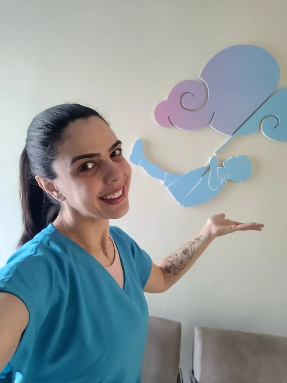 Rebeca Franz apontando para a nuvem do logotipo na parede da clínica