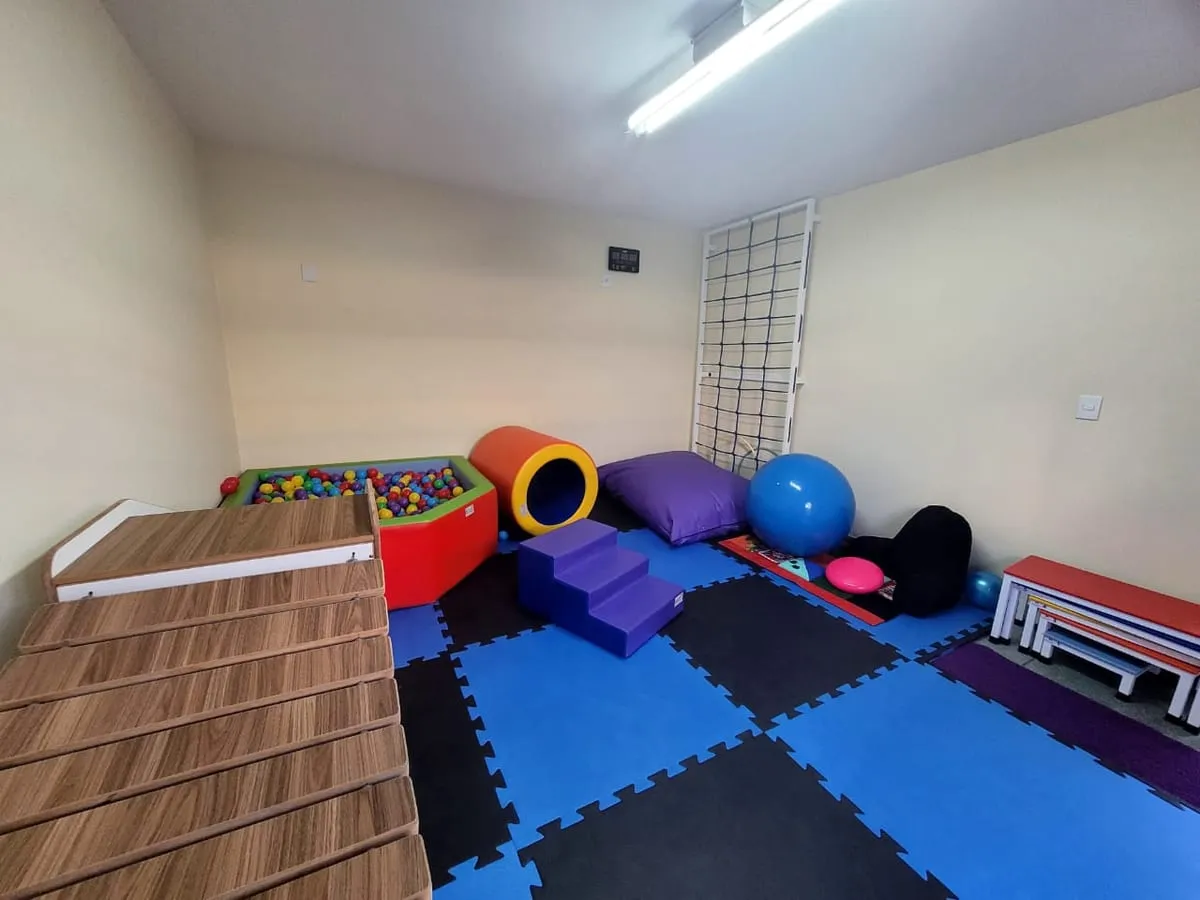 Sala de integração sensorial com piscina de bolinhas, rolos e tatame colorido