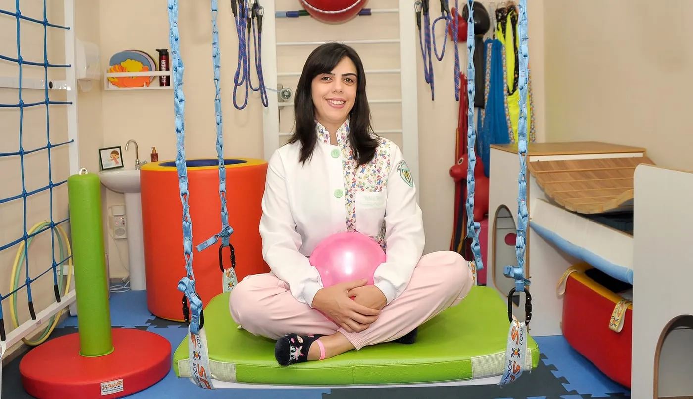 Rebeca Franz sentada no balanço da sala de integração sensorial
